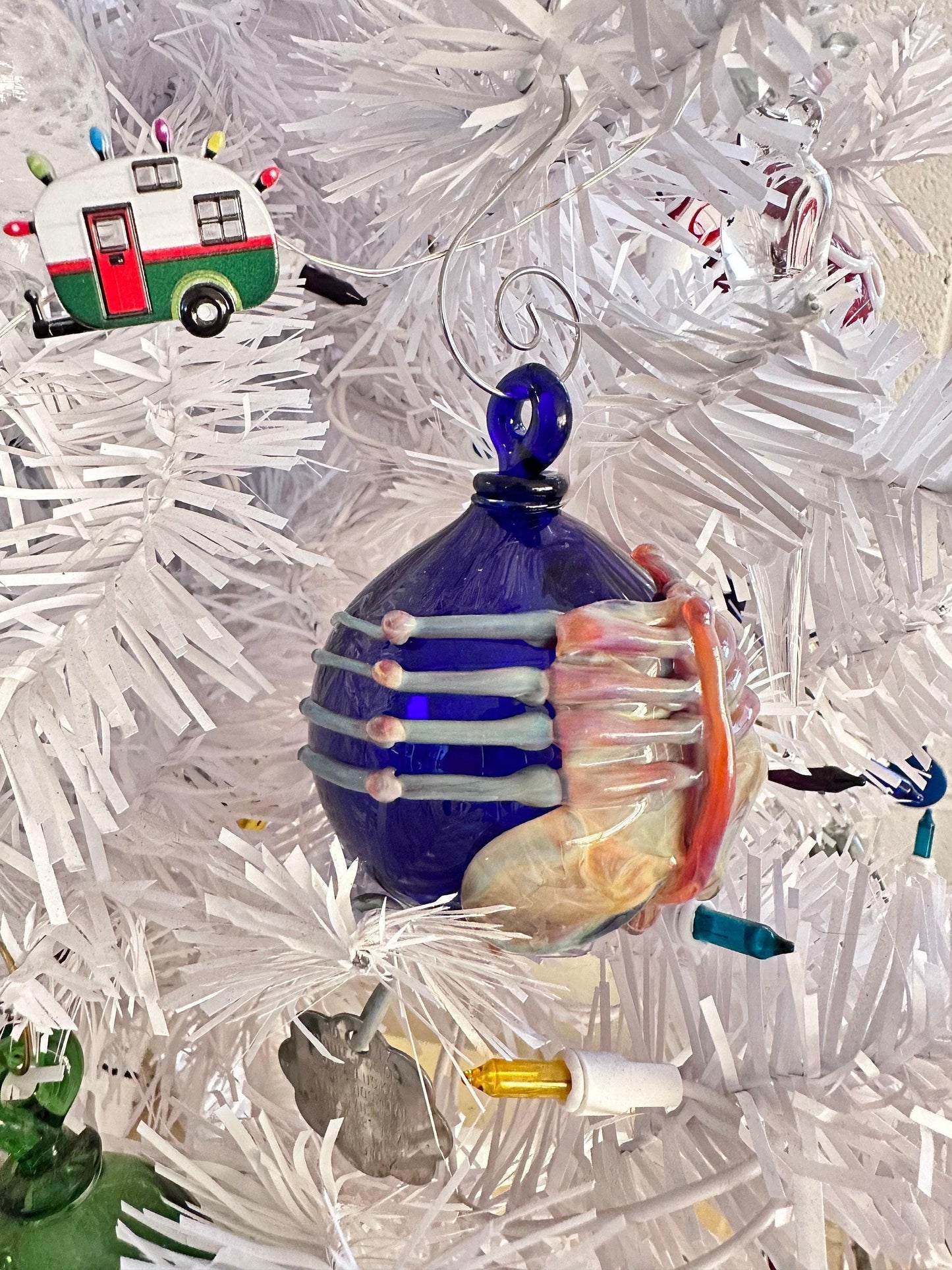 Decorative ornament with blue and pink design on a white Christmas tree.