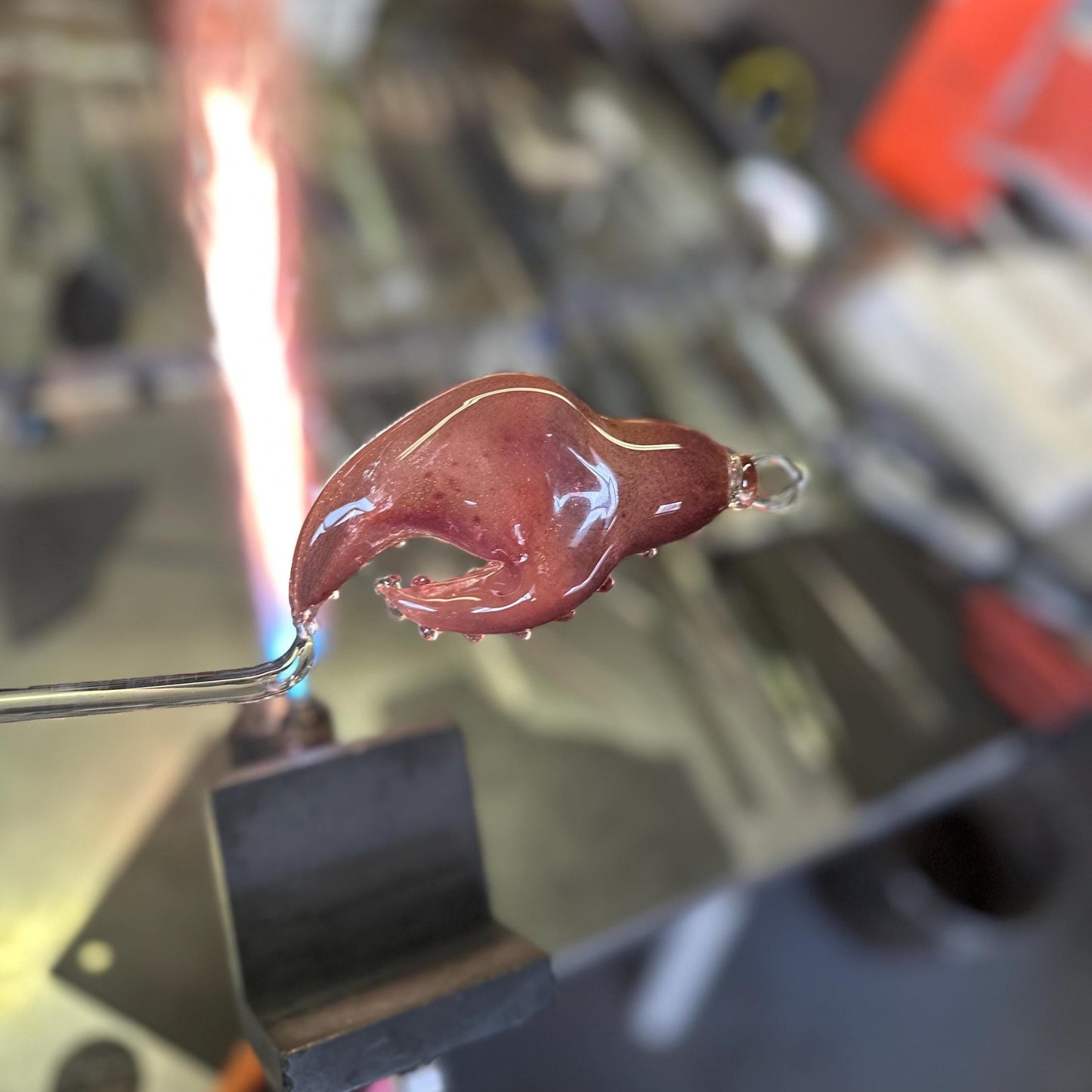 Red-hot metal object being worked on with a torch in a workshop setting