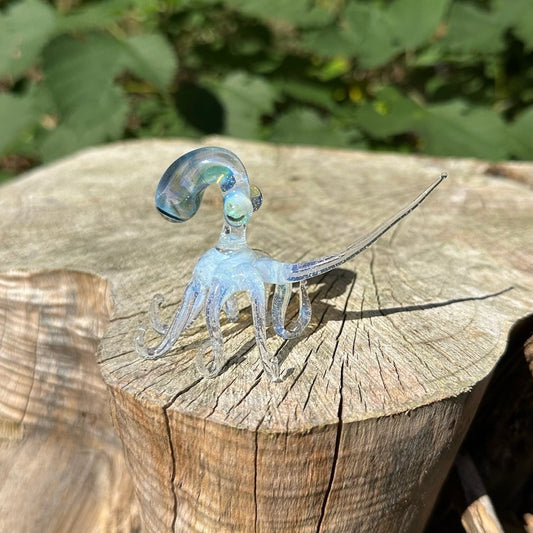 Secret white octopus figurine with leg stretched atop a wood stump. 