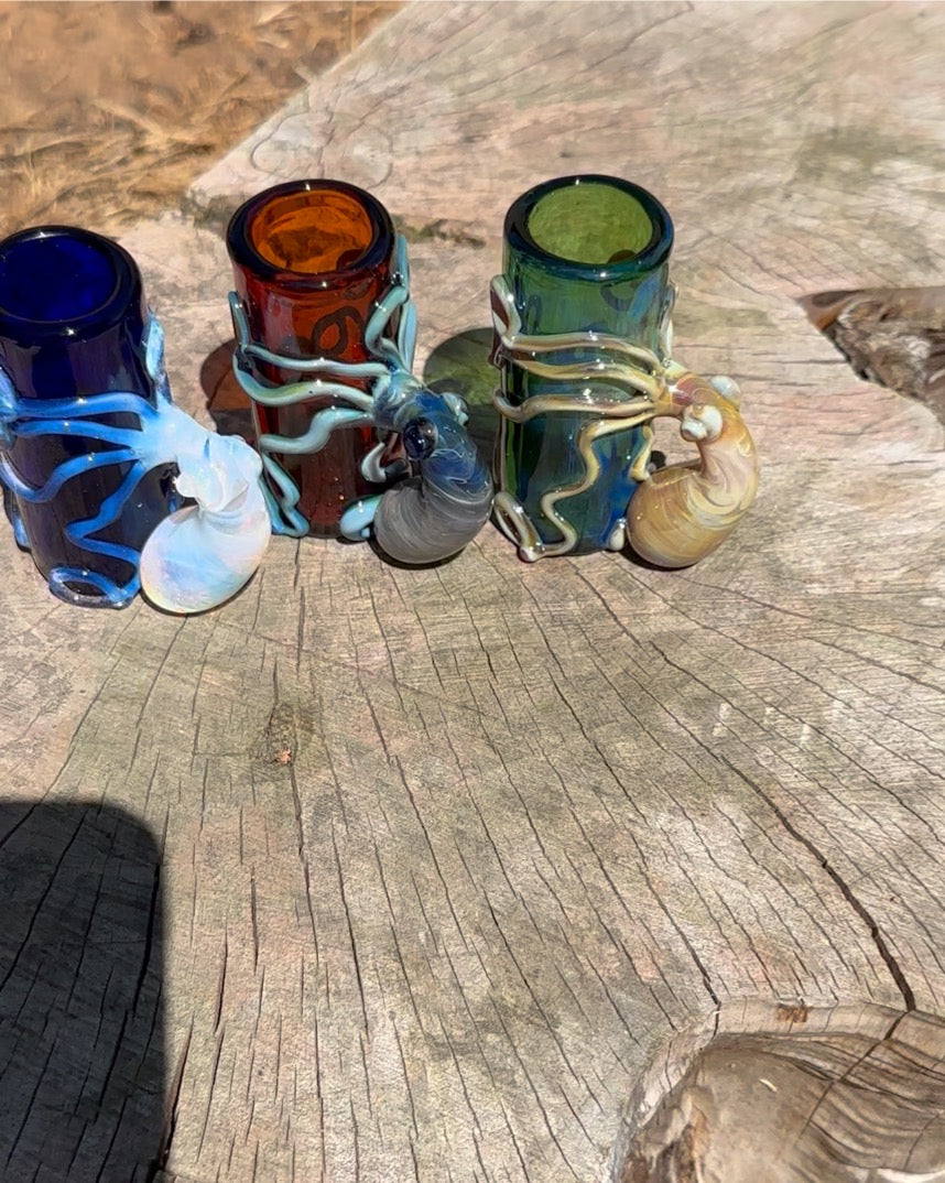 A collected of vibrant color shot glasses with octopus atop a wood stump