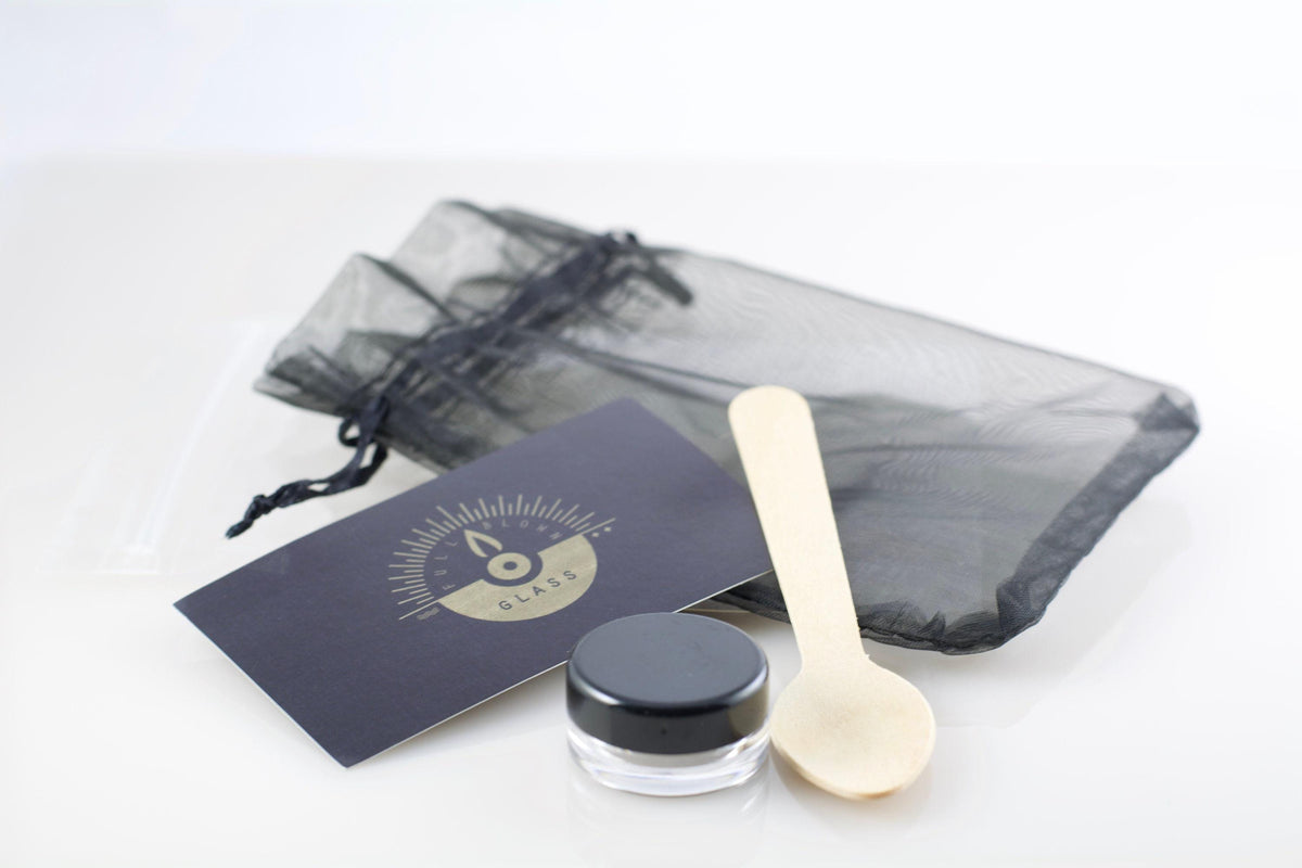 Cosmetic jar with wooden spoon and black card on a white background